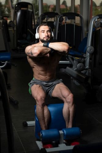 man listening to music while using a leg squat machine