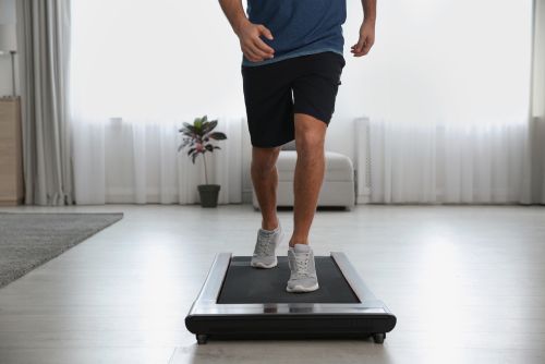 man walking on a treadmill at home protecting his knees