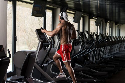 man with shirt off exercising on an elliptical building muscle 