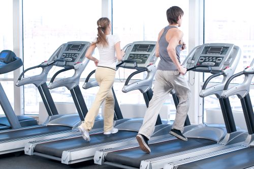 Man and lady working out how much distance is a mile on a treadmill at the gym