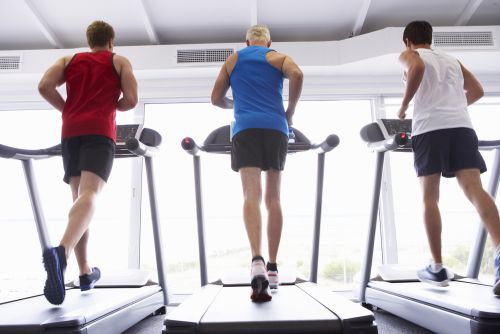 three men running on a treadmill at the gym