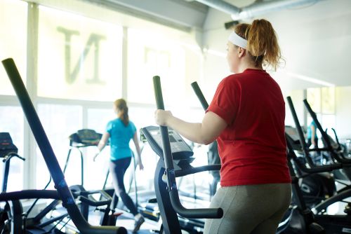 lady exercising at the gym wondering can the elliptical burn belly fat