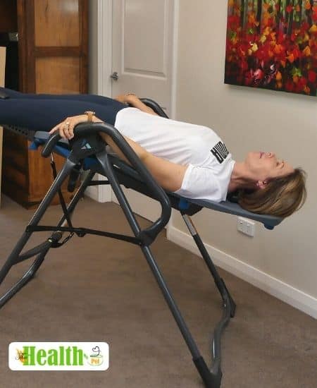 a woman lying on an inversion table that is not fully inverted upside down