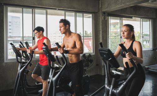 three people exercising on cross trainers at the gym
