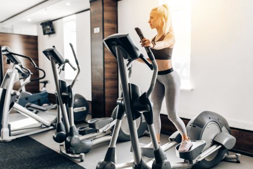 Girl at gym working out on a cross trainer