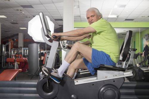A senior male using a recumbent bike in a gym