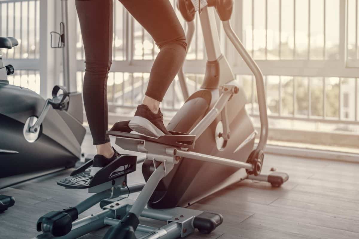legs of a male shown working out on an elliptical at the gym