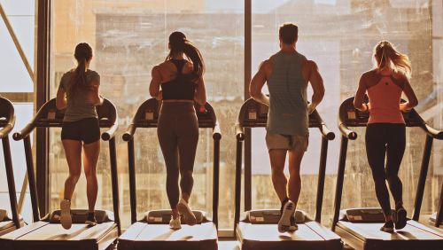 Four people at the gym running on a treadmill