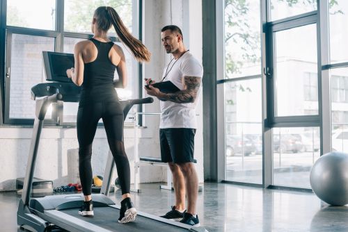 Woman using the treadmill with a personal trainer